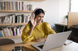 © fizkes - Positive Indian female teacher or counselor wear headphones sits at desk with laptop greeting student or client start online videocall class lecture using modern wireless technology. Virtual meeting