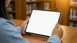 © Hendi Perkasa - Woman holds blank tablet device in library for advertising or design