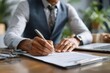 © Iftikhar alam - Applicant filling out a company application form while seated at a table with a laptop and documents during a professional setting