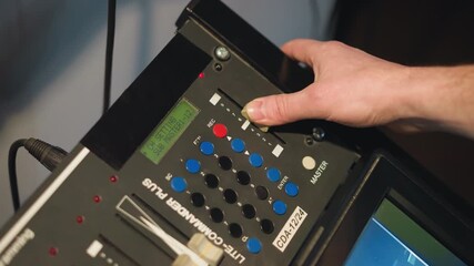Close-up shot of hand adjusting dial on professional video equipment. Setting controls on multimedia device, focusing on buttons with LED display in studio lighting, cinematic effect in action