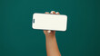 © peopleimages.com - Hands, woman and phone screen with mockup in studio for digital marketing, advertising space or UX. Mobile user, person and smartphone display on green background for coming soon deal and promotion