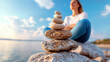 © Dararat - Serene scene of woman meditating near stack of balanced stones by water, reflecting tranquility and harmony