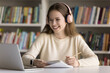© fizkes - Modern day education. Smiling teen girl college student wearing wireless earphones learning on distance take part in online class via conference app on notebook listen to lecture take written notes