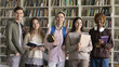 © fizkes - Education without borders. Group portrait happy successful diverse multiracial young people international high school students stand in learning space hold books workbooks look at camera with pride