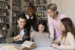 © fizkes - Creative teamwork in peer learning. Multiracial university students teens work together in classroom talk share knowledge brainstorm prepare for class project using notebook paper books written notes