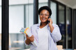 © David - African American Black woman having call on smartphone with business partner documents in hand and looking at documents at work in office, copy space