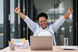 © David - Excited cheerful Black african american woman using laptop computer on sofa at workplace, getting good news, feeling joy, dancing with hands, singing, laughing, making winner gesture, happy to win pri