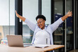 © David - Excited cheerful Black african american woman using laptop computer on sofa at workplace, getting good news, feeling joy, dancing with hands, singing, laughing, making winner gesture, happy to win pri