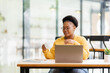 © David - Thinking about how to take the business to technological heights. Bearded smiling attractive African American Caucasian freelancer sitting in cafe, drinking fresh coffee and using lapotp.