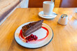 © Approved Photography - Milk and coffee with Norwegian style dark chocolate cake, thick cocoa shavings and creamy, rich milk chocolate icing on top, garnished by tart lingonberries, and encircled with sweet lingonberry sauce
