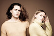 © Volodymyr - Fashion couple on beige background in studio. Couple of man with curly hair and blonde woman. Vogue Style. Youth, love and lifestyle concept. Couple in love. Young couple face to face.