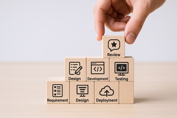 software development process depicted on wooden blocks with a hand placing the final piece