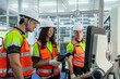 © VStudio - Three people wearing safety gear. Group of machinists in an on-the-job training session, learning to program and control an automated industrial machine.