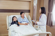 © Ekkasit A Siam - Young daughter sitting on hospital bed beside recovering mother while female doctor conducts consultation representing family support and compassionate care in pediatric-friendly hospital environment