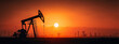 © somchairakin - Oil pumpjacks silhouetted against vibrant sunset in vast oil field, creating dramatic and industrial landscape