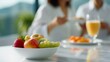 © Sheikhah - White ceramic bowl brimming with colorful fresh fruits resting on sleek marble surface, couple sharing intimate breakfast moment in soft focus background, leisurely breakfast