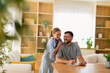 © BGStock72 - Joyful moments shared between a father and daughter while writing at home in a bright, cozy living room filled with greenery