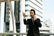 © khwanchai - A businessman in a suit stands outside a building talking on the phone with a fierce expression.