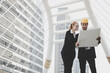 © khwanchai - Engineers and building designers stand looking at blueprints to plan the building construction design.