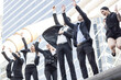 © khwanchai - Business investors in suits stand with their hands raised in celebration after achieving their goals outside an office building.