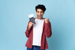 © luismolinero - Young Venezuelan man isolated on blue background happy in vacation with passport and plane tickets