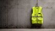 © Dina - Bright yellow safety vest hangs on gray wall