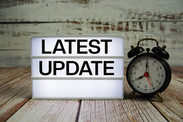 Latest Update text on light box with alarm clock on wooden background