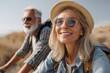 © Cheewynn - Smiling older couple enjoying a sunny outdoor adventure, wearing sunglasses and hats while biking through a scenic landscape