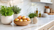 © M - Fresh apples and herbs in decorative pots on a modern marble kitchen countertop with dining items in the background