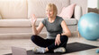 © Prostock-studio - Positive mature woman in sportswear sitting on yoga mat in front of laptop, greeting her personal trainer before training. Senior lady communicating with fitness instructor, ready for home workout