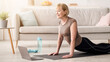 © Prostock-studio - Domestic yoga concept. Flexible mature lady doing cobra asana on sports mat, training to online tutorial on laptop, indoors. Senior woman keeping in good shape during coronavirus quarantine