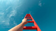 © Ada - Development Attainment Motivation Career Growth Concept. hand grasping a bright red wooden ladder. The ladder extends diagonally upwards into a vast, clear blue sky dotted with scattered wispy clouds