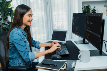 Young Asian in IT developer creating with typing online information on pc with coding program data of website application, wearing jeans shirt. surrounded by safety analysis two screens. Stratagem.