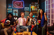 © pressmaster - Group of multiethnic young adults cheering and celebrating while watching sports game on television, holding drinks and snacks, showing excitement and enthusiasm in living room setting