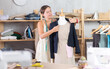 © JackF - Female seamstress puts jacket on mannequin. Handmade clothes, unique wardrobe items, family manufactory. Sewing workshop, girl works as designer at small enterprise. .