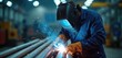 © Vadym - Welder in blue jumpsuit and safety helmet works with welding torch. Sparks fly around him in industrial setting with machinery and equipment. Man in protective gear welds metal pipe.