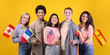 © Prostock-studio - Student exchange, language learning, international holiday. Smiling multi ethnic student in casual, hold small flags of different countries, isolated on orange background, free space, studio shot