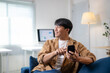© Wasana - A man is sitting on a couch and holding a cell phone