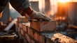 © Sarqiah - Worker laying bricks in sunny construction site for construction or real estate use