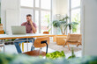 © Westend61 - Confident professional using laptop and phone in modern office workspace