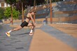 © master1305 - Woman performing stretches outside during workout on sunny day. Concept of strength building, plank training, female determination, and lean power.