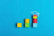 © Irina_Evva - Graduation and education concept with colorful blocks and academic cap on a blue background. Symbol of learning, growth, and academic achievement