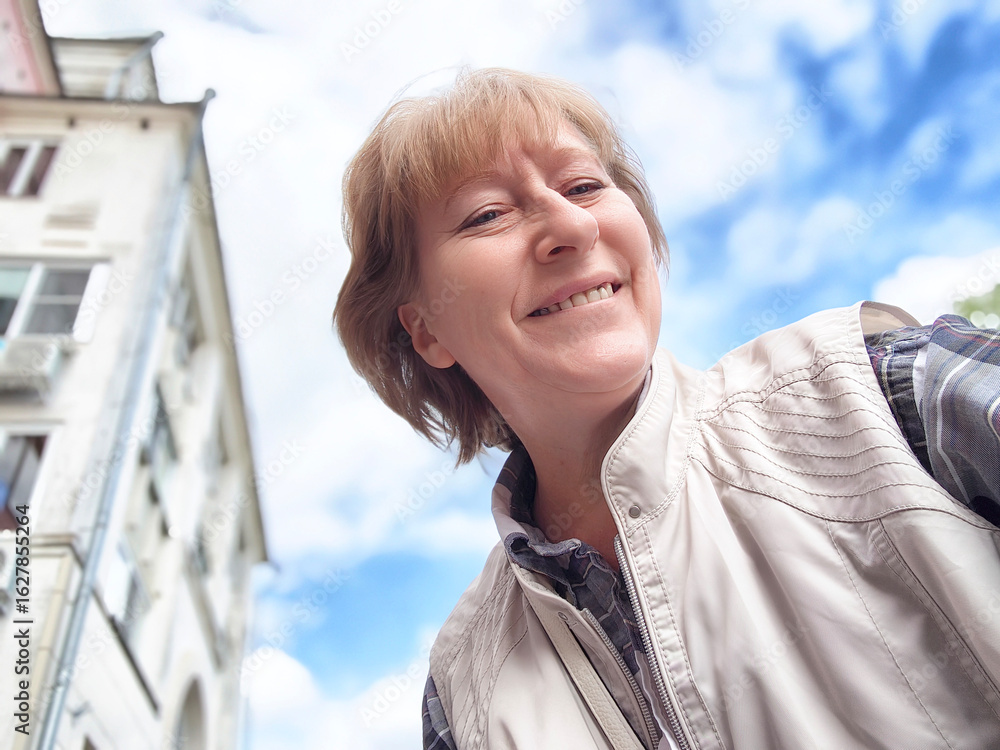 Blonde woman enjoys a sunny excursion while capturing a selfie in a ...