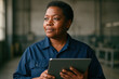 © smth.design - confident female engineer in blue uniform holding tablet and looking away inside industrial workspace with equipment in background