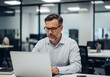 © Akbar Hossain - Focused Businessman Working on Laptop in Modern Office Environment Achieving Goals and Driving Business Success
