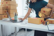 © Nittaya - Home Business Fulfillment: A small business owner meticulously organizes and processes packages for shipping, showcasing the behind-the-scenes work of e-commerce and entrepreneurial endeavor.
