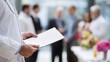 © Justlight - Focused image of the hematologyoncology specialist holding a certificate white coat prominent with a blurred crowd and floral decorations symbolizing new cancercare expertise.