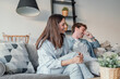 © Daniel - Young happy couple having fun talking laughing relaxing at home on couch, boyfriend embracing girlfriend telling funny joke sitting on sofa, humor in relationships, enjoying weekend together