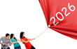 © Creativa Images - Group of young people pulling a rope to reveal a red banner with the year 2026.
