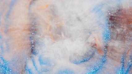 Wall Mural - macro view of brown glitter ink blending with swirling white smoke in water. the visual creates soft